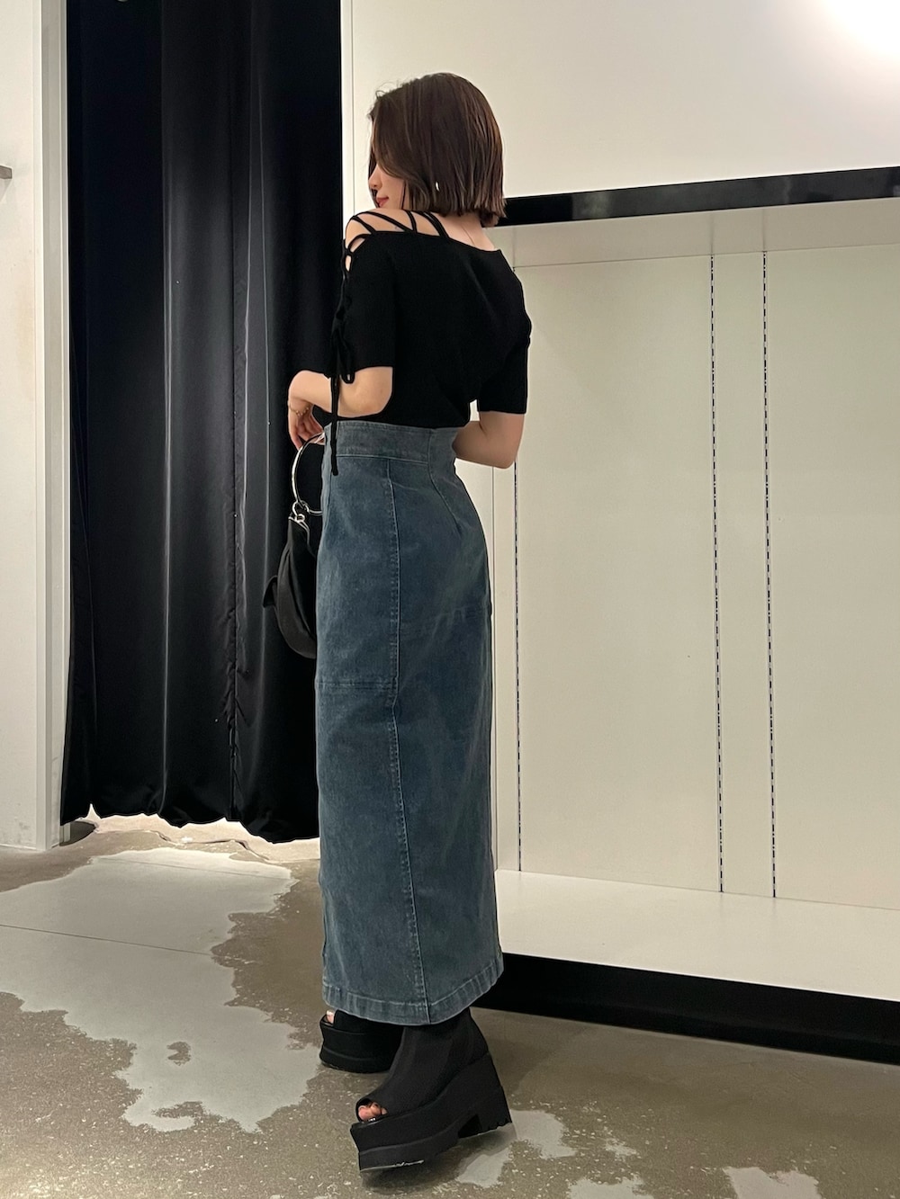 ブルー系のデニムスカート、ブラック系のニット/セーター、ブラック系のサンダルを着用したレディースの夏コーディネートの2枚目の写真