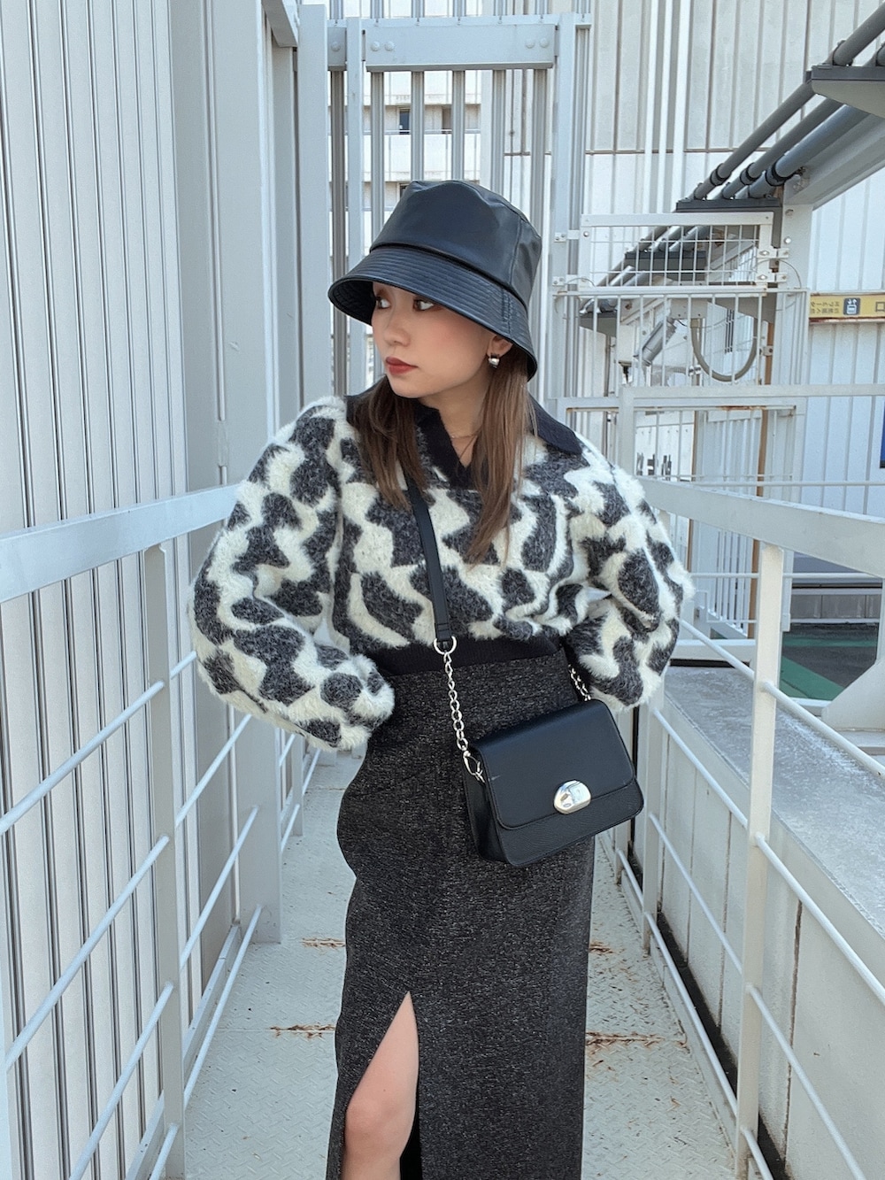 ブラック系のニット/セーター、ブラック系のスカート、ブラック系のショルダーバッグを着用したレディースの秋コーディネートの5枚目の写真