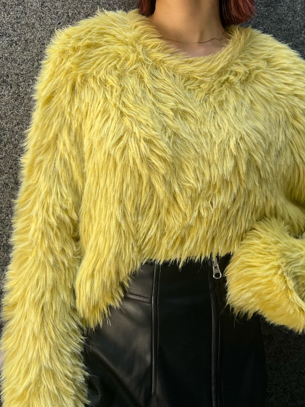 イエロー系のニット/セーター、ブラック系のスカート、ブラック系のブーツを着用したレディースの秋コーディネートの8枚目の写真