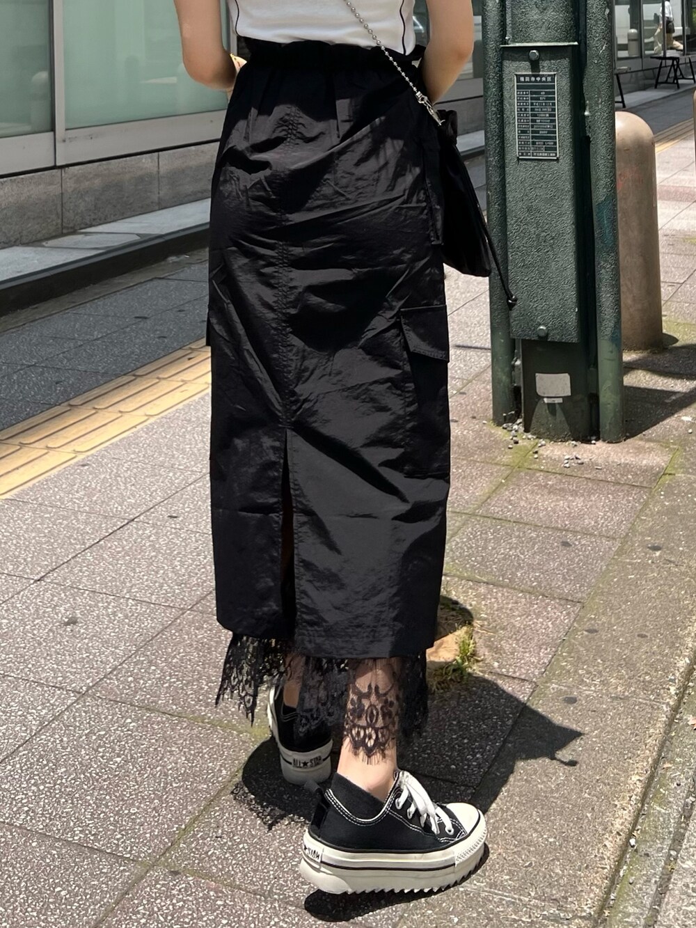 ブラック系のスカート、ブラック系のショルダーバッグ、ホワイト系のTシャツ/カットソーを着用したレディースの夏コーディネートの6枚目の写真