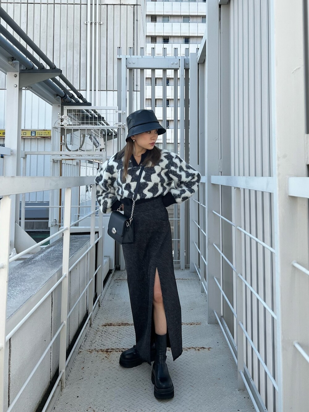 ブラック系のニット/セーター、ブラック系のスカート、ブラック系のショルダーバッグを着用したレディースの秋コーディネートの4枚目の写真