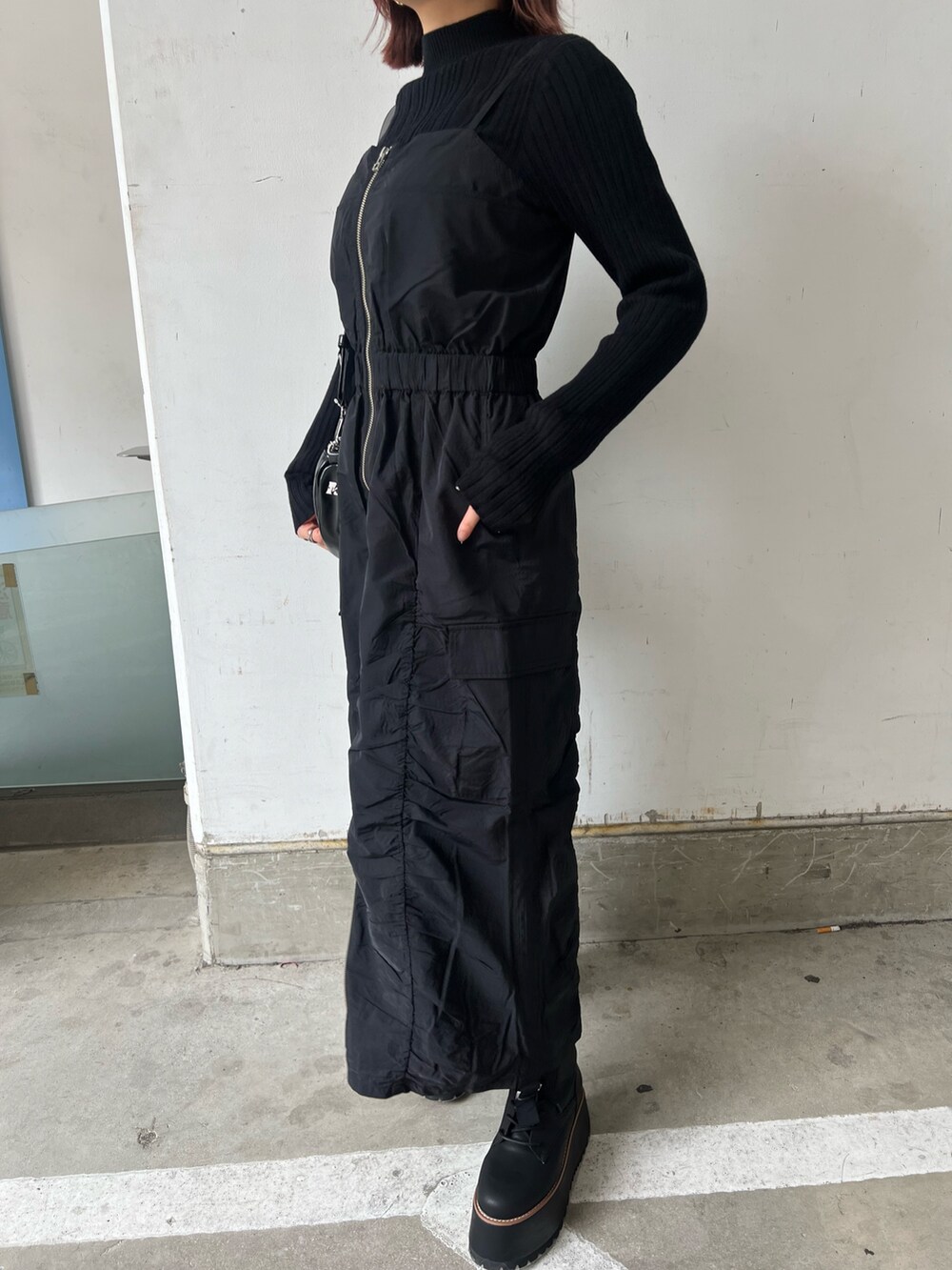 ブラック系のワンピース、ブラック系のブーツ、ブラック系のニット/セーターを着用したレディースの冬コーディネートの4枚目の写真