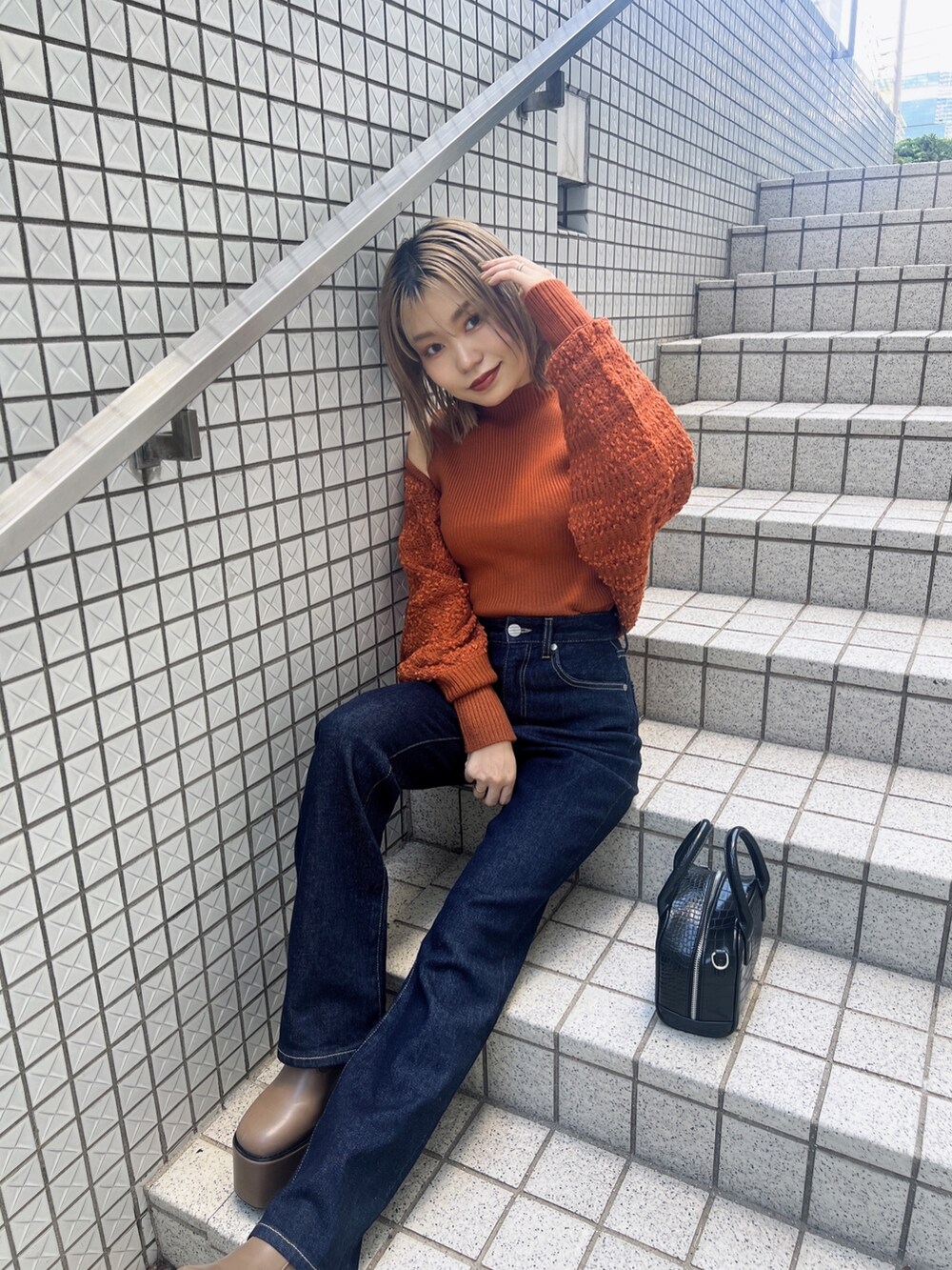 オレンジ系のカーディガン/ボレロ、ブルー系のデニムパンツ、ブラウン系のブーツを着用したレディースの夏コーディネートの3枚目の写真