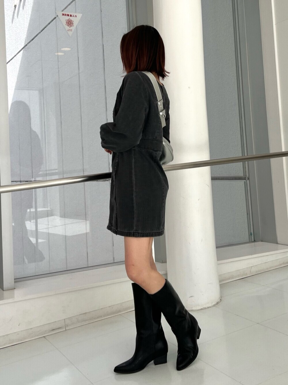 シルバー系のショルダーバッグ、ブラック系のワンピース、ブラック系のブーツを着用したレディースの冬コーディネートの4枚目の写真