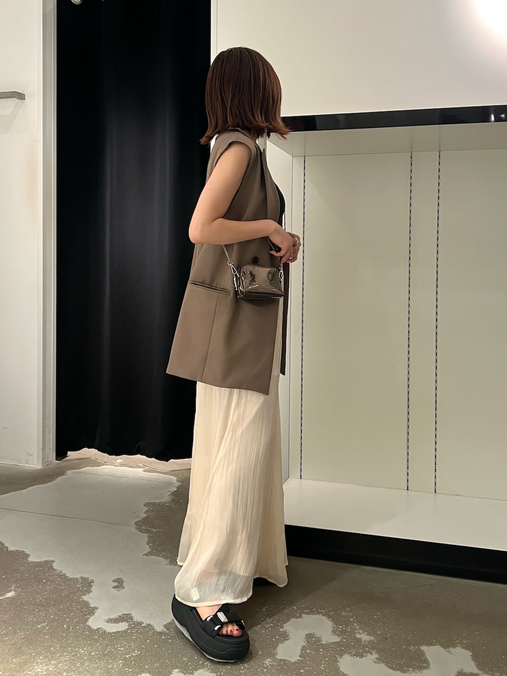 ブラック系のサンダル、ホワイト系のスカート、ゴールド系のショルダーバッグを着用したレディースの夏コーディネートの2枚目の写真