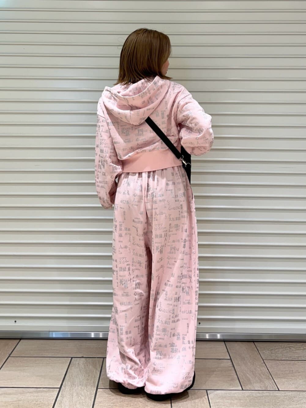 ピンク系のセットアップ、ブラック系のショルダーバッグを着用したレディースの春コーディネートの3枚目の写真