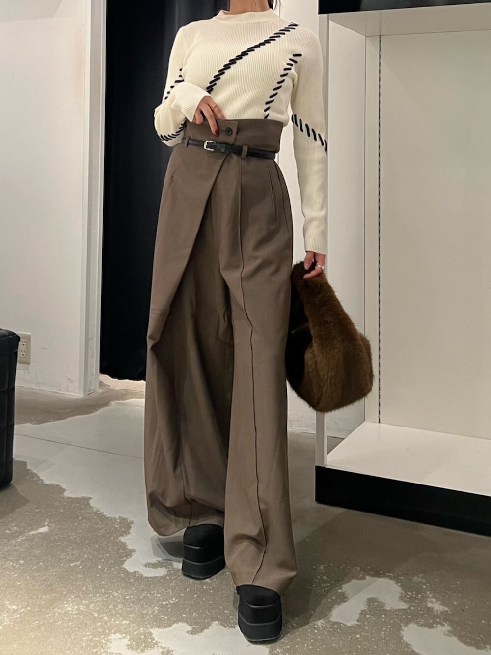 ホワイト系のニット/セーター、ブラック系のブーツ、ブラウン系のハンドバッグを着用したレディースの秋コーディネートの4枚目の写真