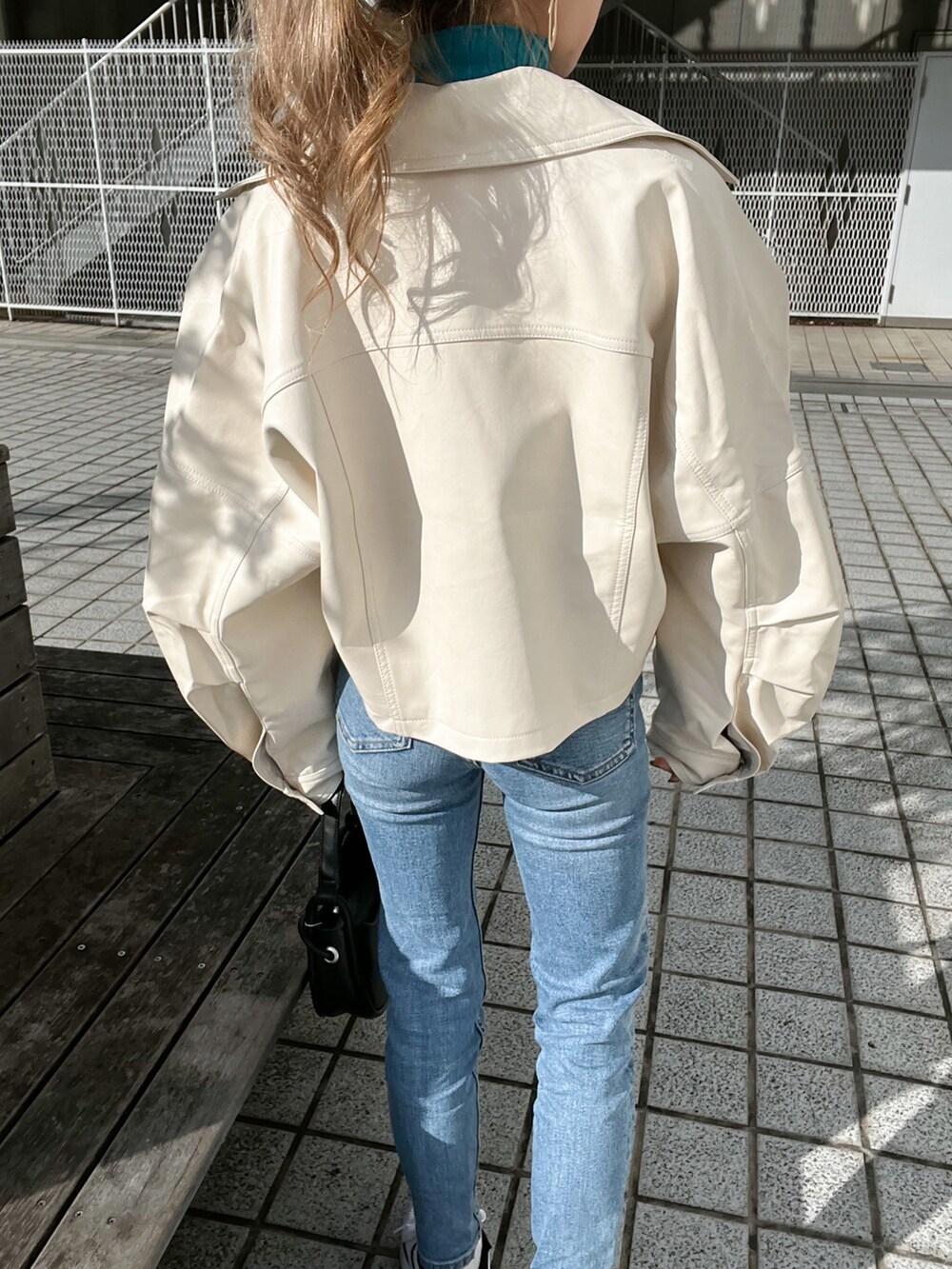 ホワイト系のライダースジャケット、ブルー系のニット/セーター、ブラック系のハンドバッグを着用したレディースの冬コーディネートの8枚目の写真