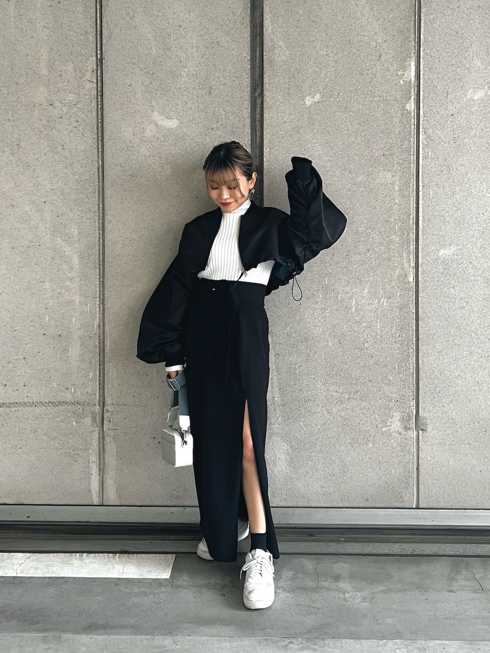 ブラック系のMA-1、ホワイト系のニット/セーター、ブラック系のスカートを着用したレディースの冬コーディネートの2枚目の写真