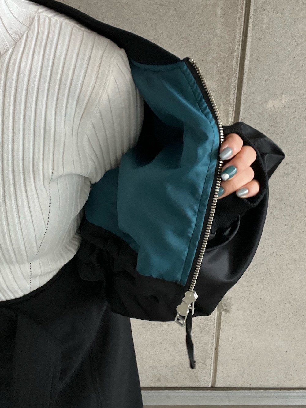 ブラック系のMA-1、ホワイト系のニット/セーター、ブラック系のスカートを着用したレディースの冬コーディネートの8枚目の写真