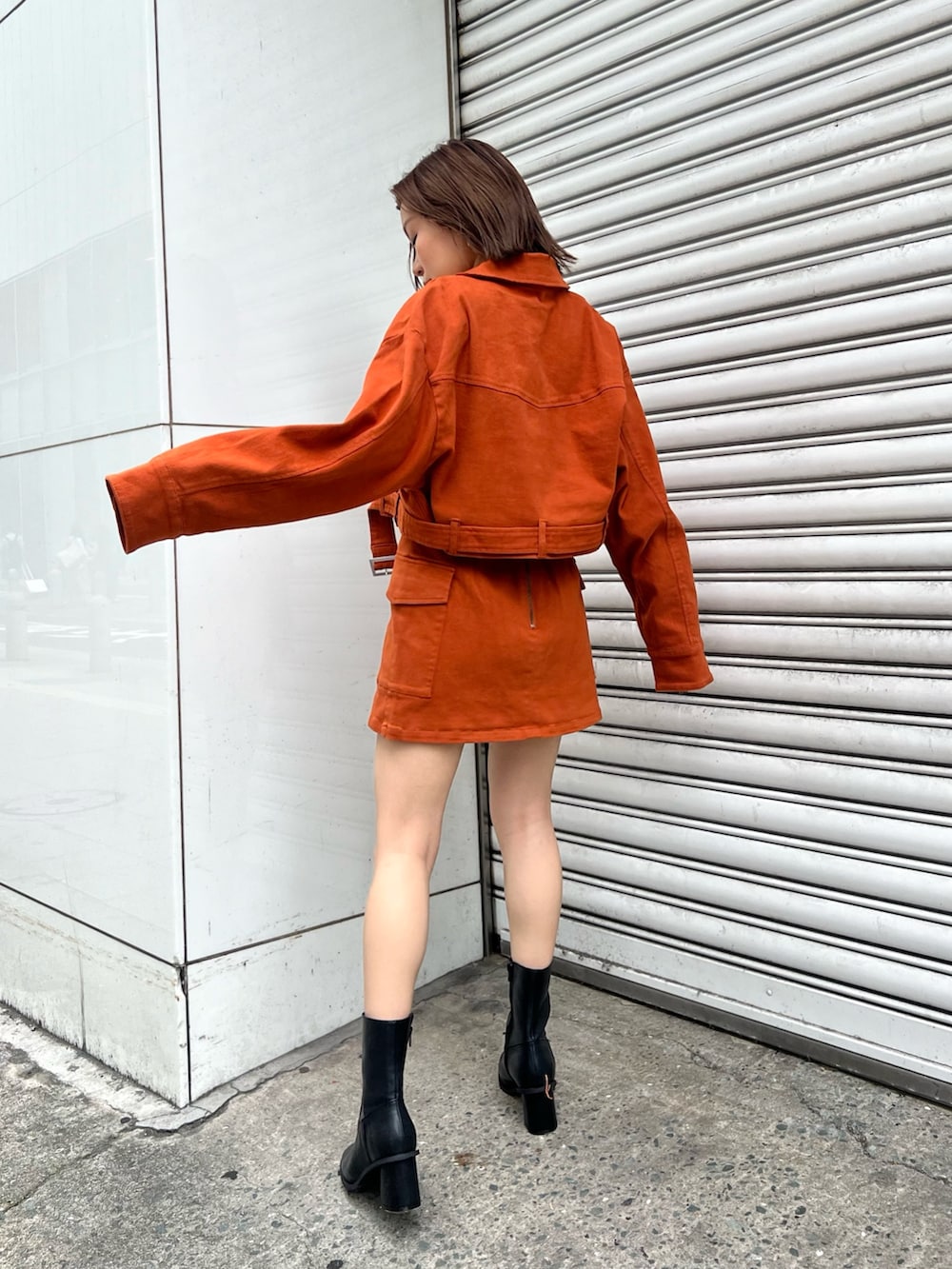 ホワイト系のニット/セーター、オレンジ系のデニムジャケット、オレンジ系のスカートを着用したレディースの夏コーディネートの2枚目の写真