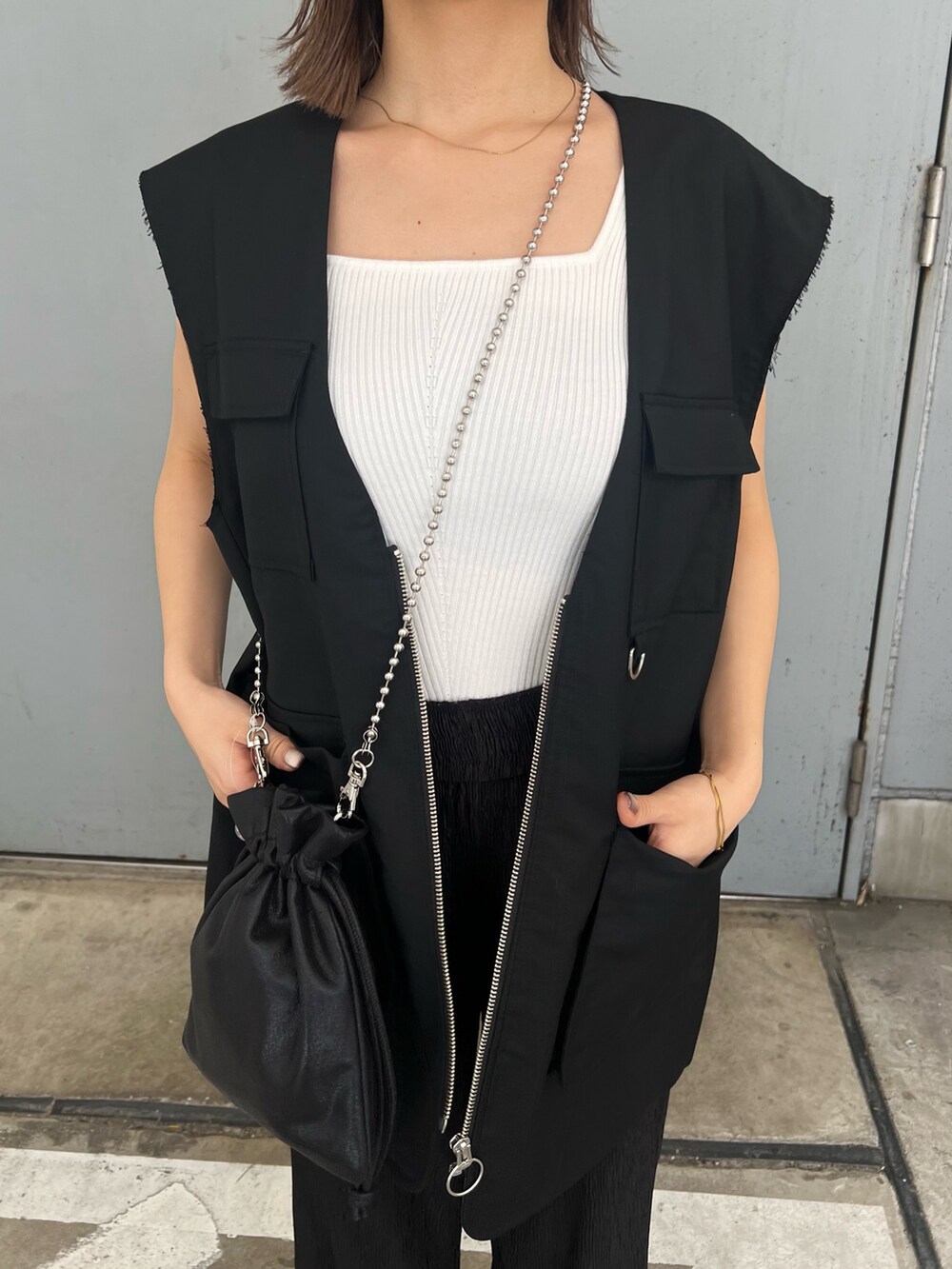 ブラック系のベスト、ホワイト系のニット/セーター、ブルー系のキャップを着用したレディースの夏コーディネートの8枚目の写真