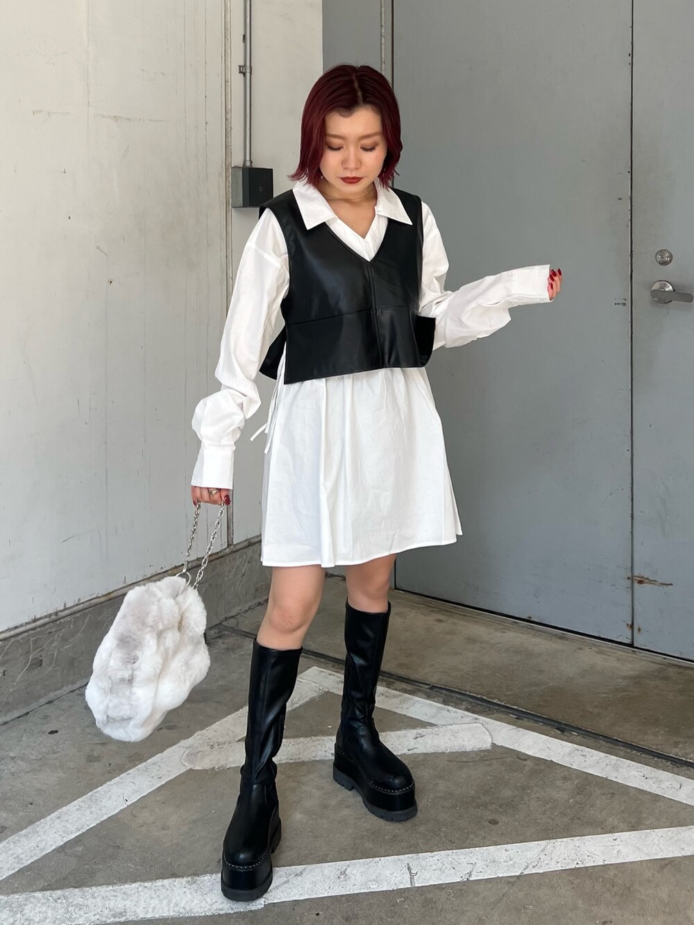 ベージュ系のハンドバッグ、ブラック系のワンピース、ブラック系のブーツを着用したレディースの秋コーディネートの3枚目の写真