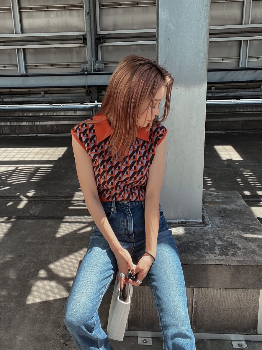 ブルー系のデニムパンツ、オレンジ系のニット/セーター、ホワイト系のブーツを着用したレディースの夏コーディネートの3枚目の写真