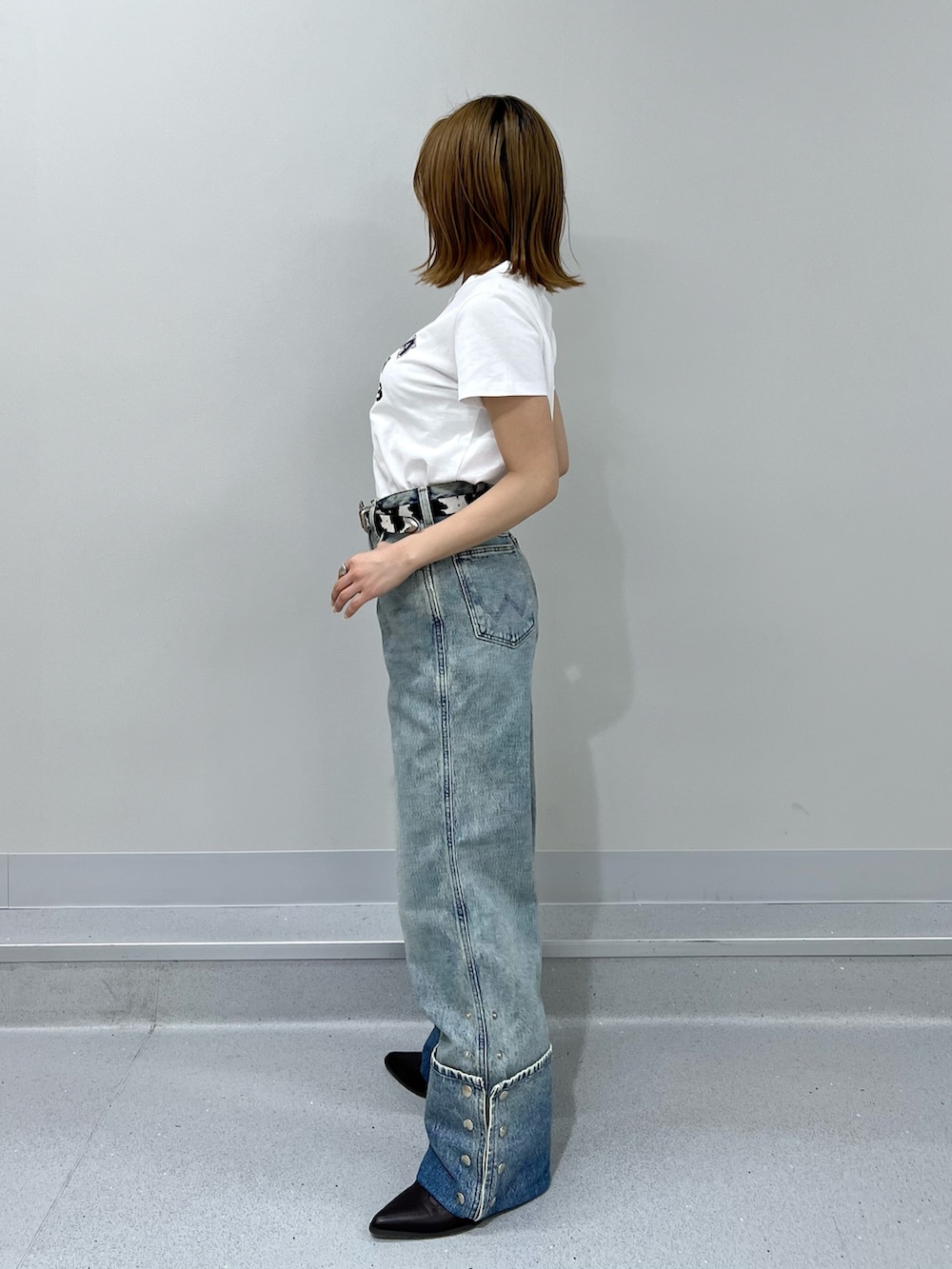 ブルー系のデニムパンツ、ホワイト系のTシャツ/カットソー、ブラウン系のブーツを着用したレディースの春コーディネートの2枚目の写真