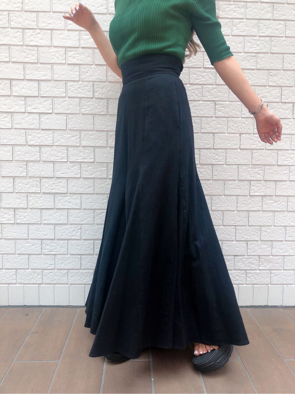 ブラック系のスカート、グリーン系のニット/セーター、ブラック系のハットを着用したレディースの夏コーディネートの4枚目の写真