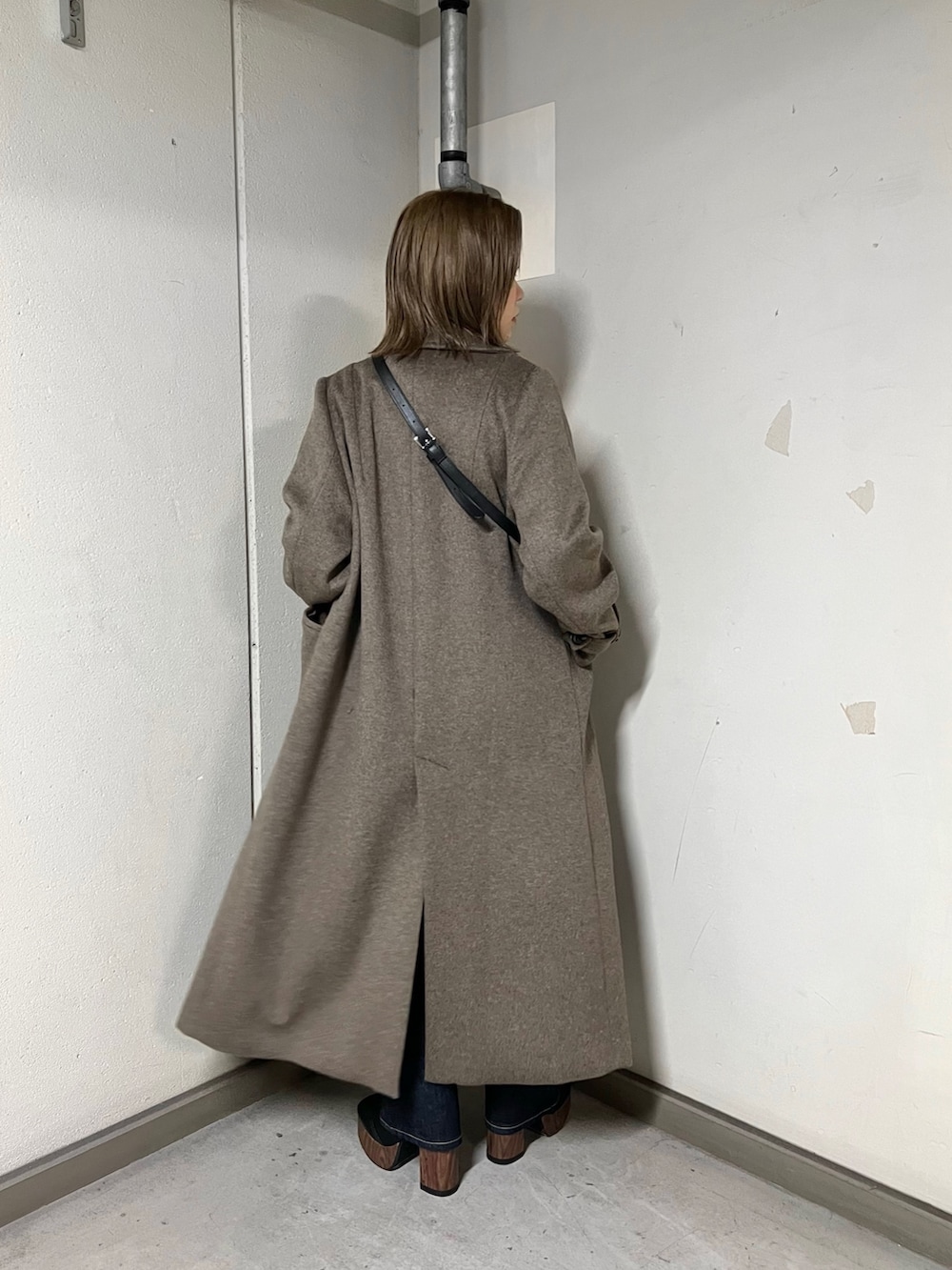 ブルー系のデニムパンツ、ブラウン系のチェスターコート、レッド系のニット/セーターを着用したレディースの秋コーディネートの3枚目の写真