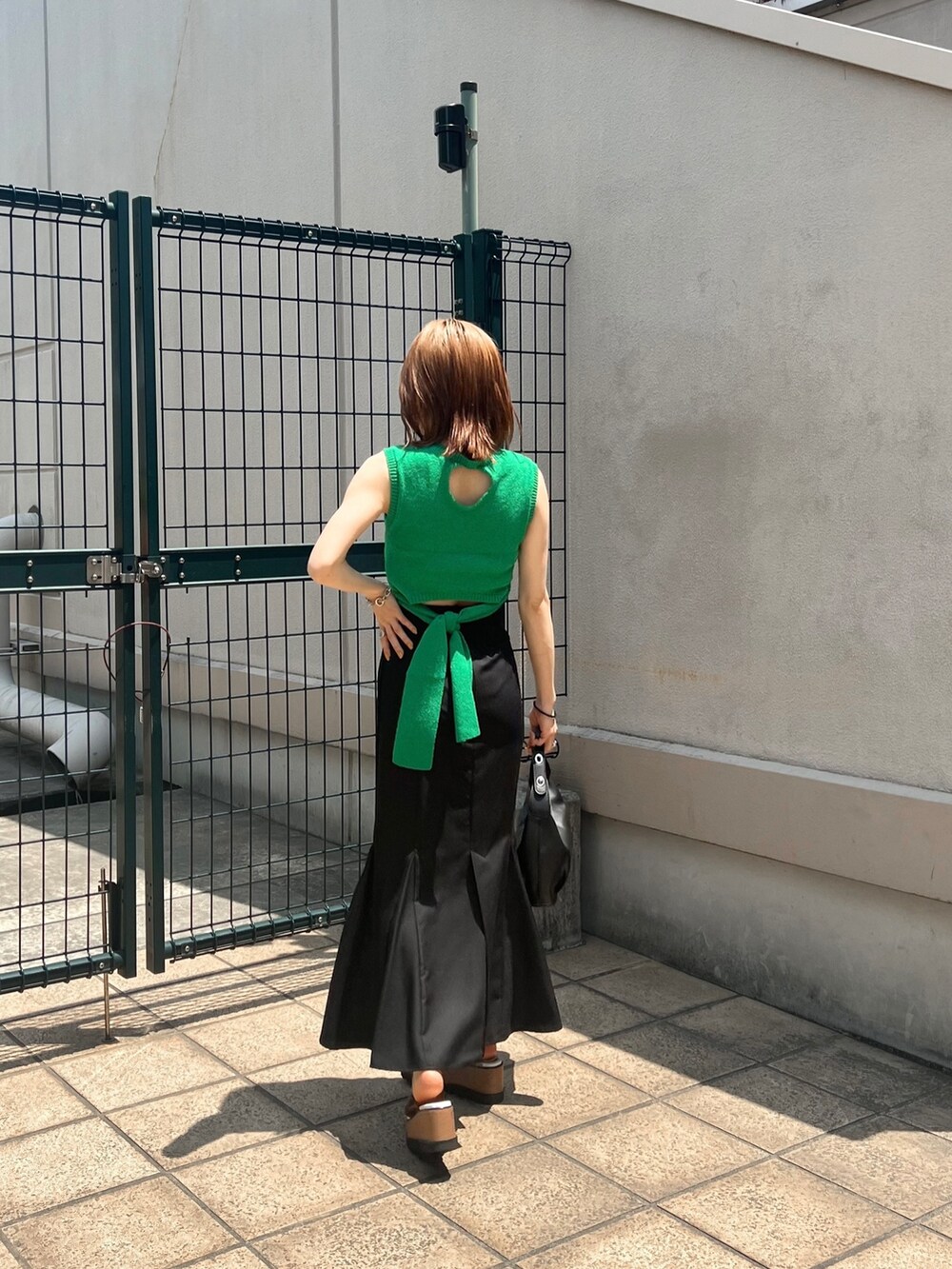 グリーン系のタンクトップ、ブラック系のスカート、その他のサンダルを着用したレディースの夏コーディネートの2枚目の写真