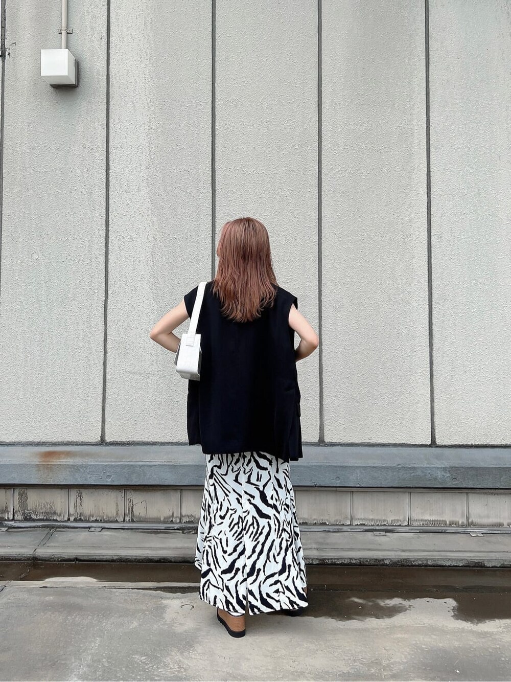 その他のサンダル、ブラック系のベスト、ホワイト系のハンドバッグを着用したレディースの夏コーディネートの3枚目の写真