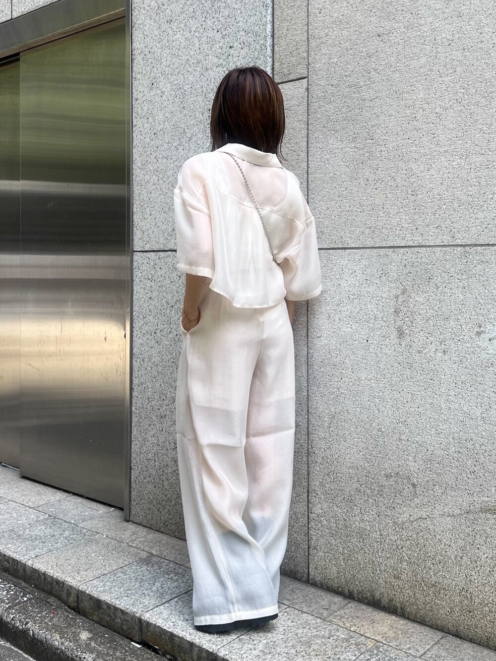 ホワイト系のシャツ/ブラウス、ホワイト系のニット/セーター、ブラック系のショルダーバッグを着用したレディースの夏コーディネートの3枚目の写真