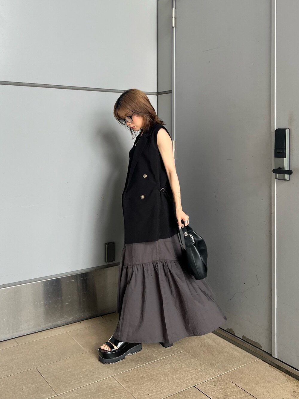 ブラック系のベスト、ブラック系のニット/セーター、グレー系のスカートを着用したレディースの夏コーディネートの4枚目の写真