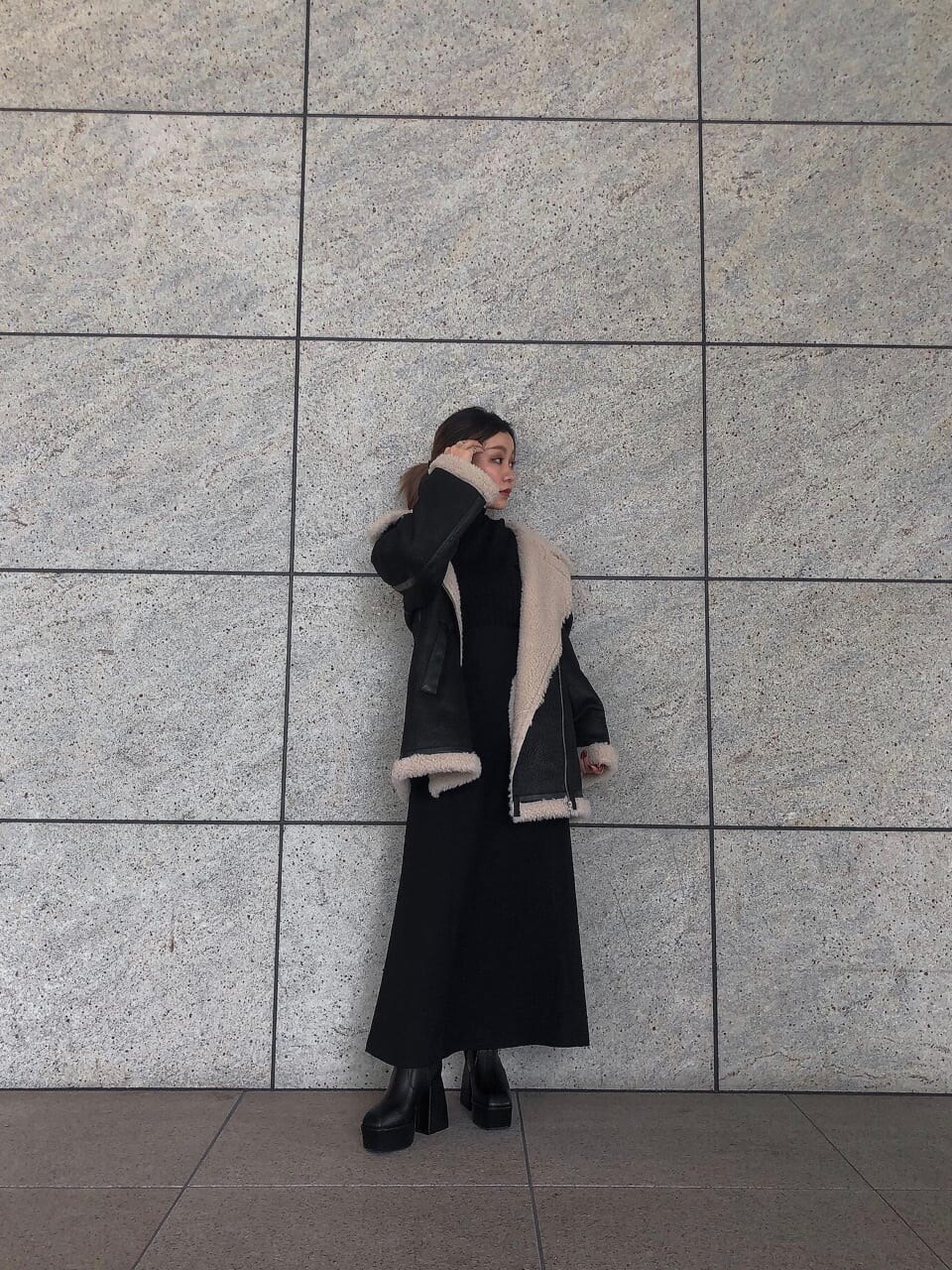 ブラック系のスカート、ブラック系のブルゾン、ブラック系のブーツを着用したレディースの秋コーディネートの2枚目の写真