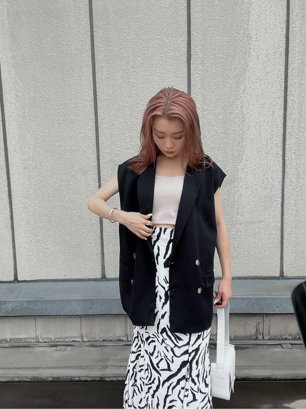 その他のサンダル、ブラック系のベスト、ホワイト系のハンドバッグを着用したレディースの夏コーディネートの4枚目の写真