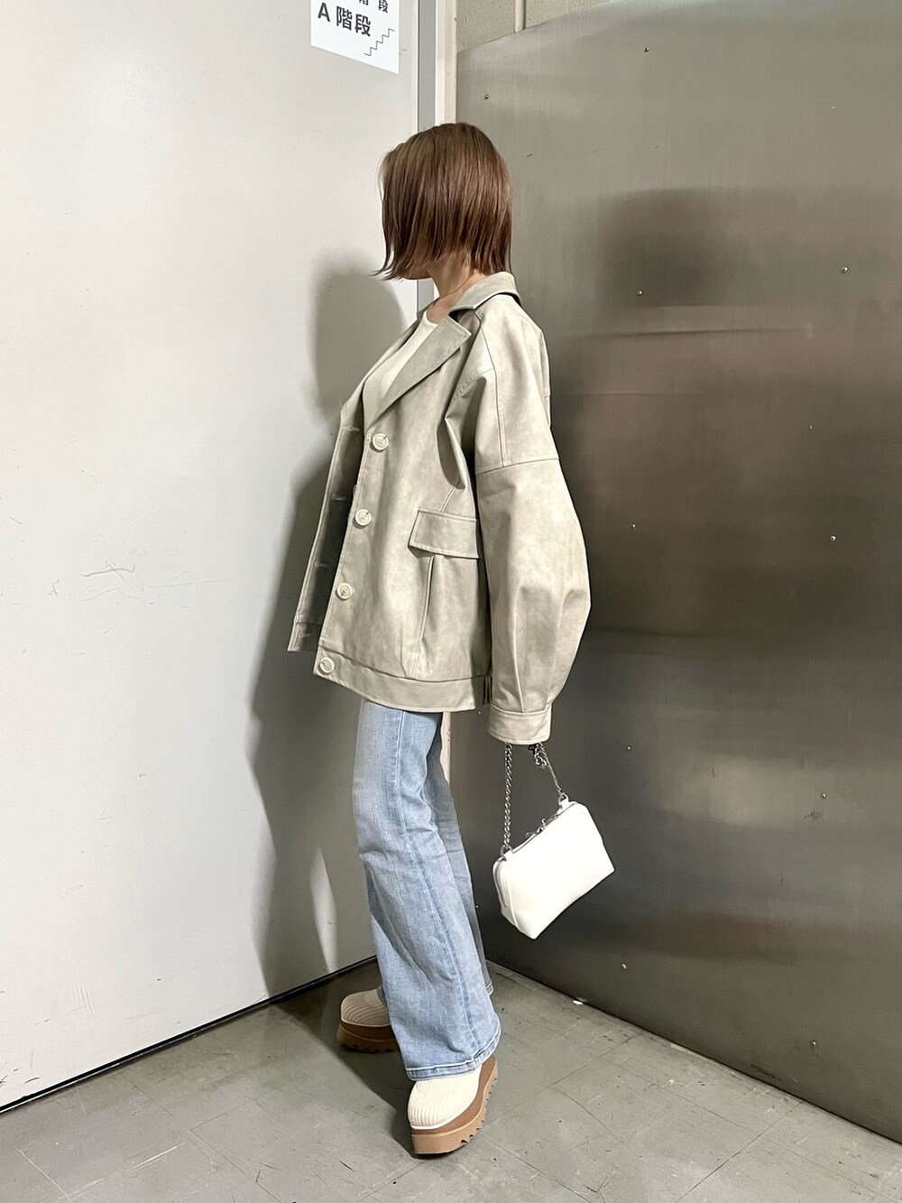 ホワイト系のブルゾン、ホワイト系のニット/セーター、ホワイト系のハンドバッグを着用したレディースの冬コーディネートの2枚目の写真