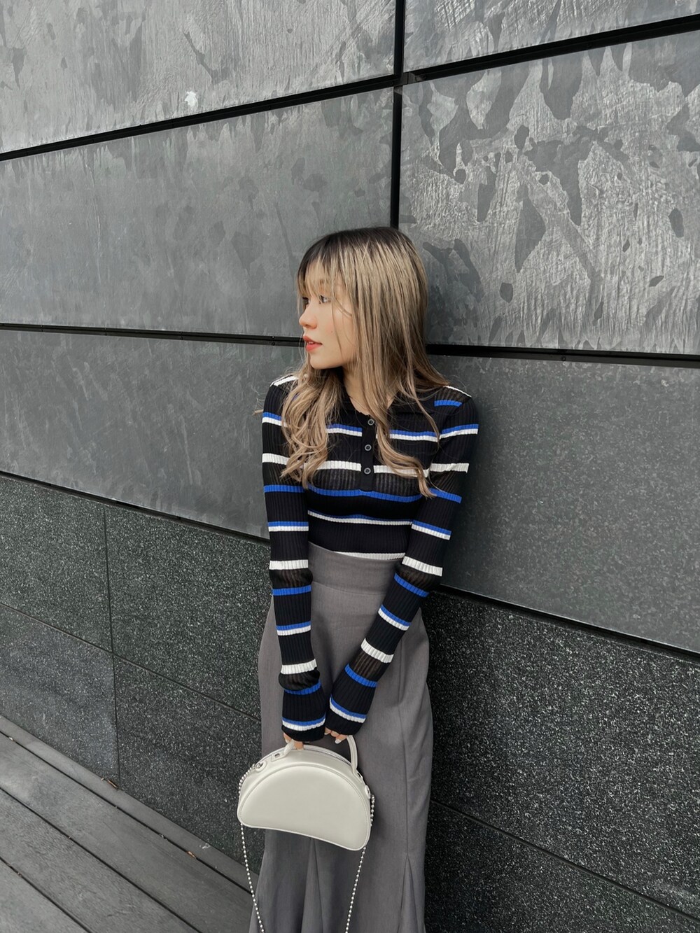 ブルー系のポロシャツ、グレー系のスカート、ブラック系のブーツを着用したレディースの春コーディネートの5枚目の写真