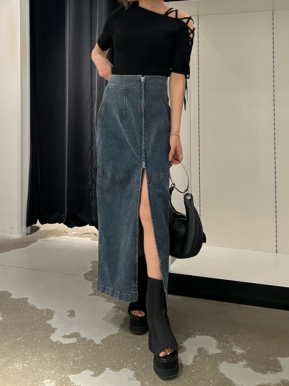 ブルー系のデニムスカート、ブラック系のニット/セーター、ブラック系のサンダルを着用したレディースの夏コーディネートの8枚目の写真