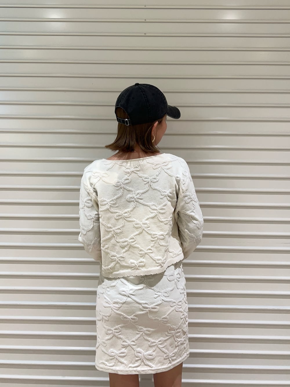 ホワイト系のワンピース、ホワイト系のカーディガン/ボレロ、ブラック系のキャップを着用したレディースの冬コーディネートの5枚目の写真