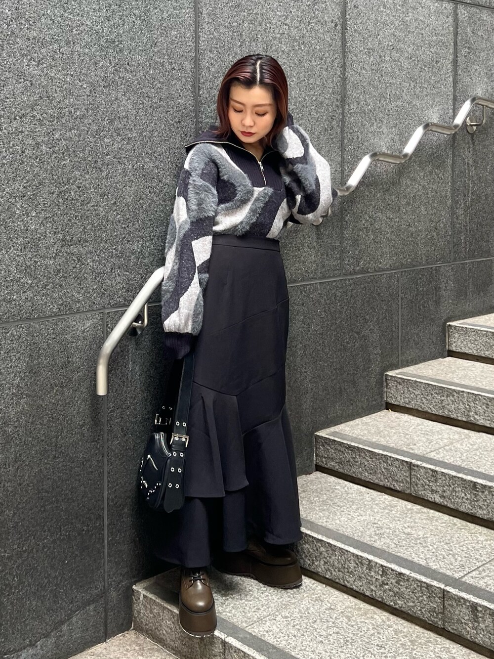 ブラック系のニット/セーター、ブラウン系のブーツ、ブラック系のスカートを着用したレディースの秋コーディネートの3枚目の写真