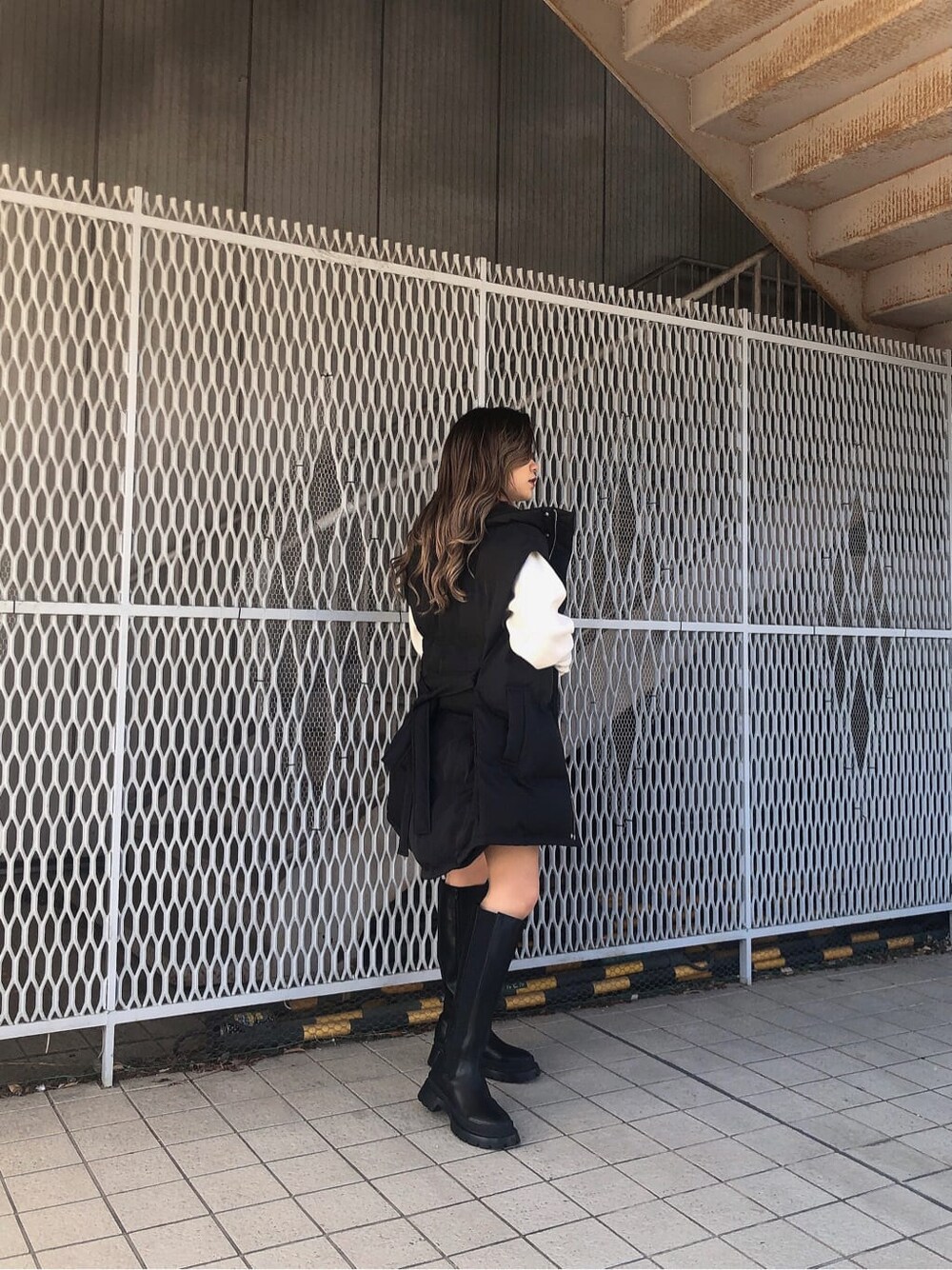 グレー系のその他パンツ、ブラック系のブーツ、ブラック系のダウンベストを着用したレディースの秋コーディネートの3枚目の写真