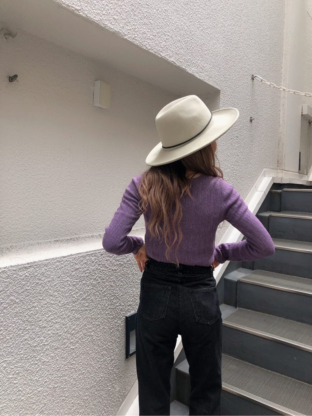 ホワイト系のブーツ、パープル系のニット/セーター、ブラック系のデニムパンツを着用したレディースの秋コーディネートの4枚目の写真