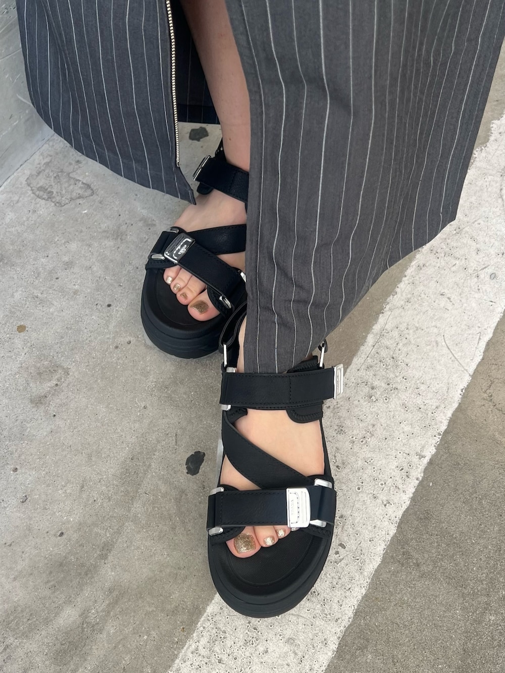 ホワイト系のベスト、ブラック系のタンクトップ、グレー系のスカートを着用したレディースの春コーディネートの8枚目の写真