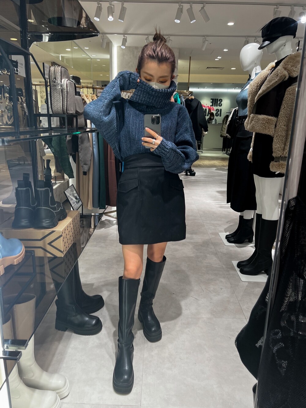 ブラック系のスカート、ブルー系のニット/セーター、ブラック系のブーツを着用したレディースの秋コーディネートの2枚目の写真