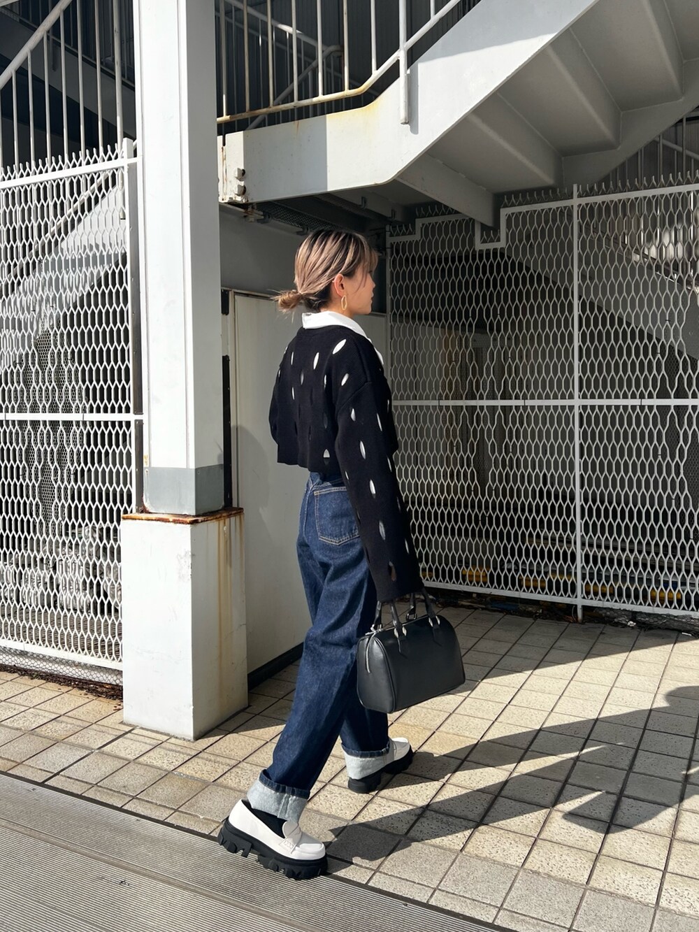 ブルー系のデニムパンツ、ホワイト系のローファー、ブラック系のニット/セーターを着用したレディースの冬コーディネートの2枚目の写真