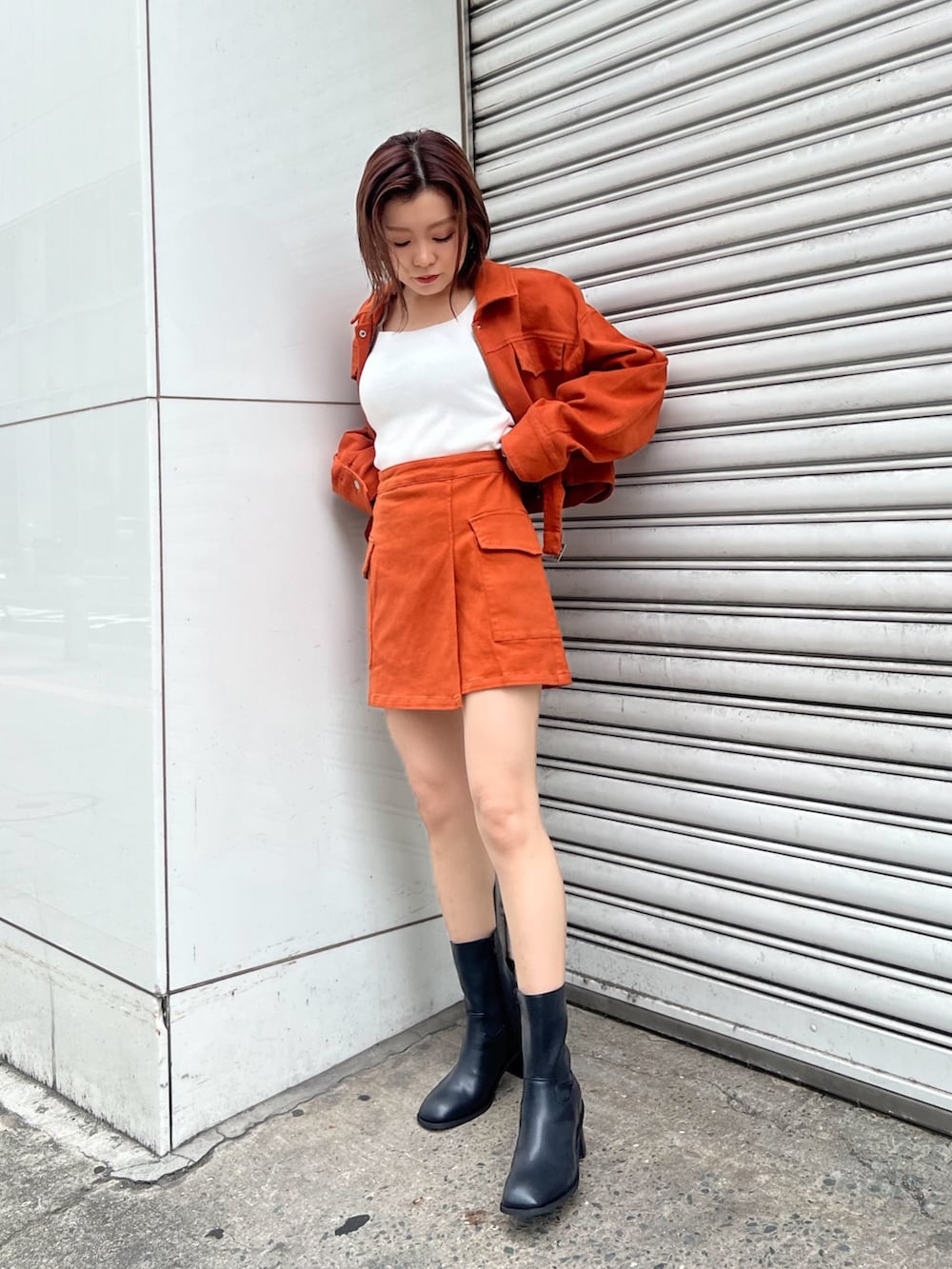 ホワイト系のニット/セーター、オレンジ系のデニムジャケット、オレンジ系のスカートを着用したレディースの夏コーディネートの3枚目の写真