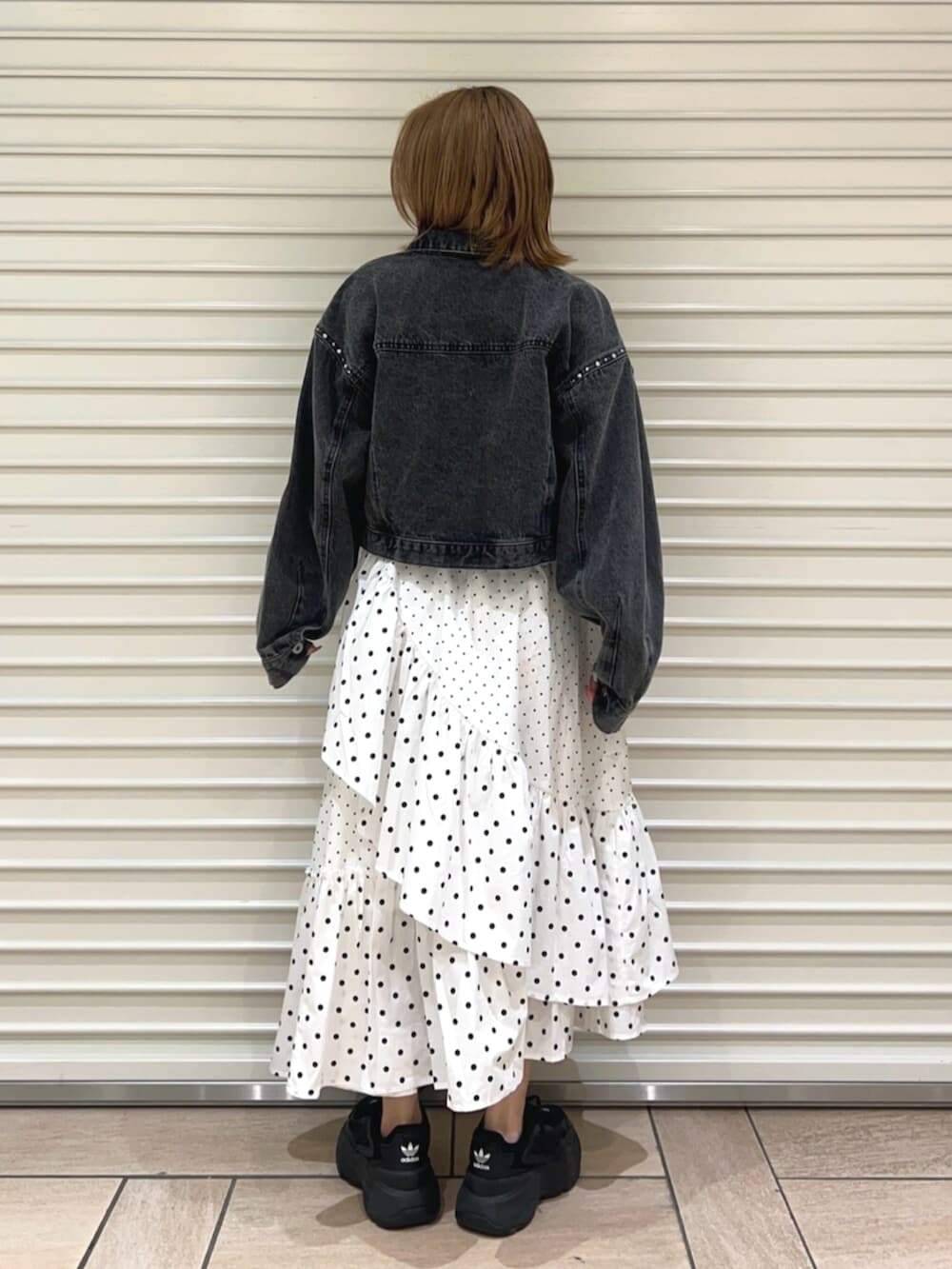 イエロー系のTシャツ/カットソー、ブラック系のデニムジャケット、ホワイト系のスカートを着用したレディースの春コーディネートの3枚目の写真