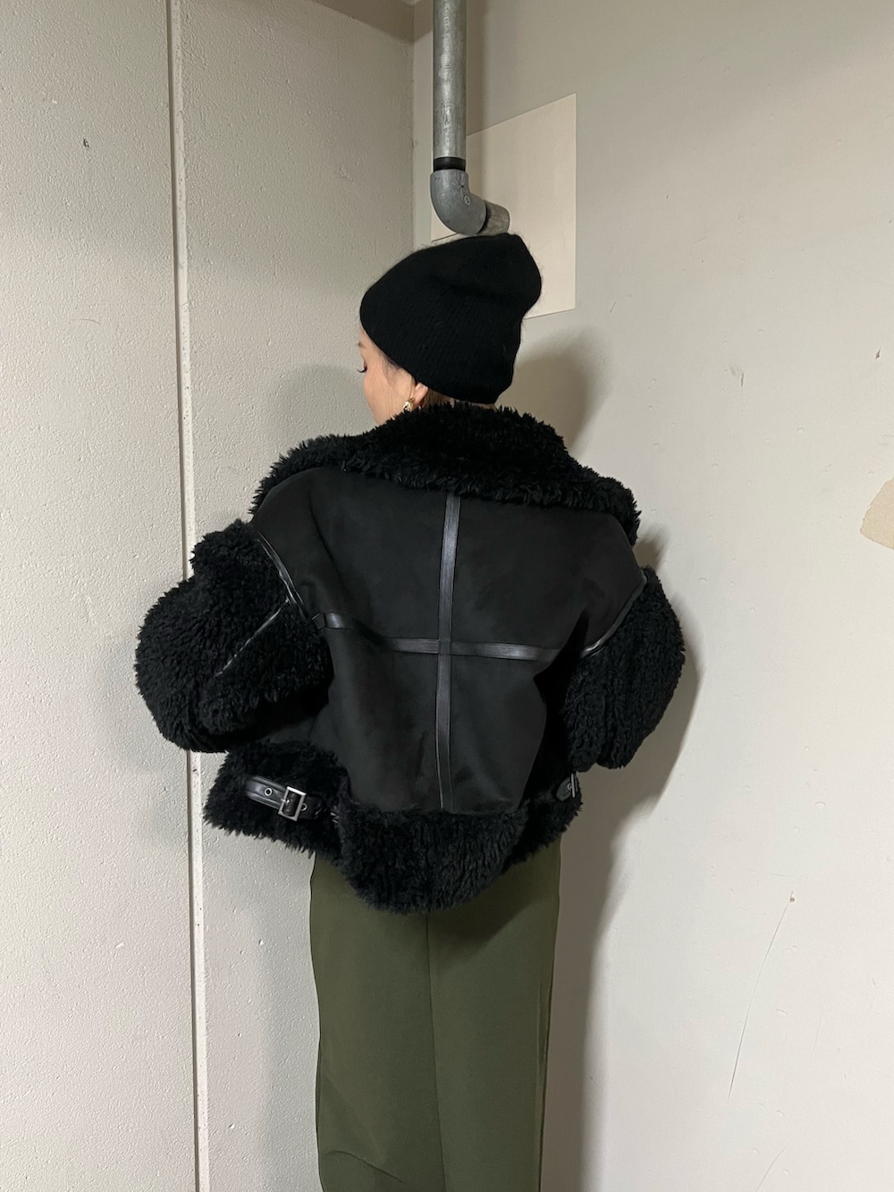 ブラック系のムートンコート、ブラック系のニット/セーター、グリーン系のスカートを着用したレディースの冬コーディネートの5枚目の写真