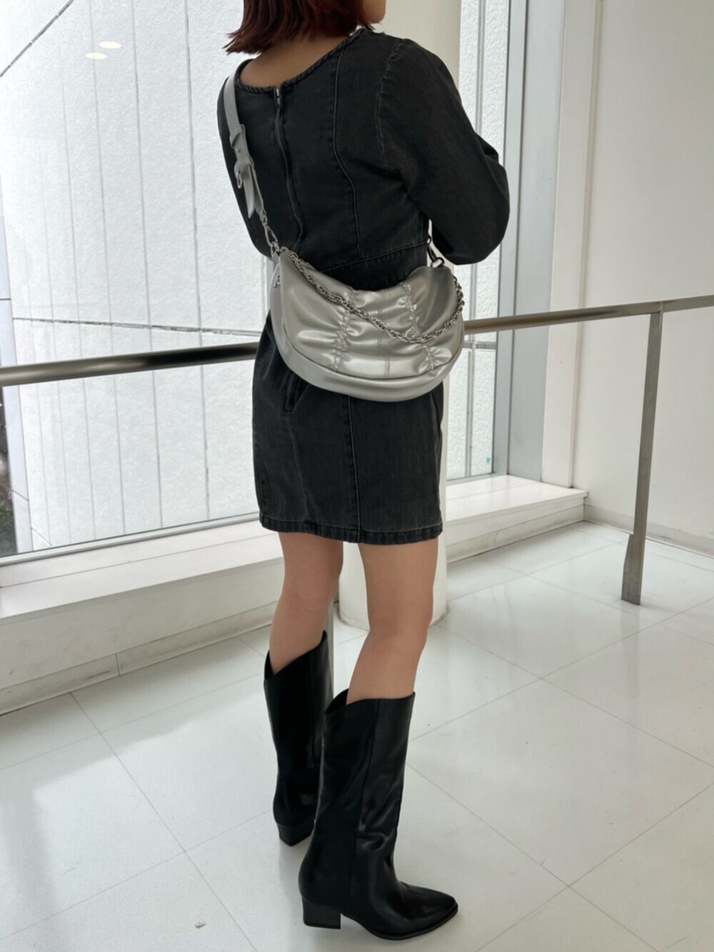 シルバー系のショルダーバッグ、ブラック系のワンピース、ブラック系のブーツを着用したレディースの冬コーディネートの7枚目の写真