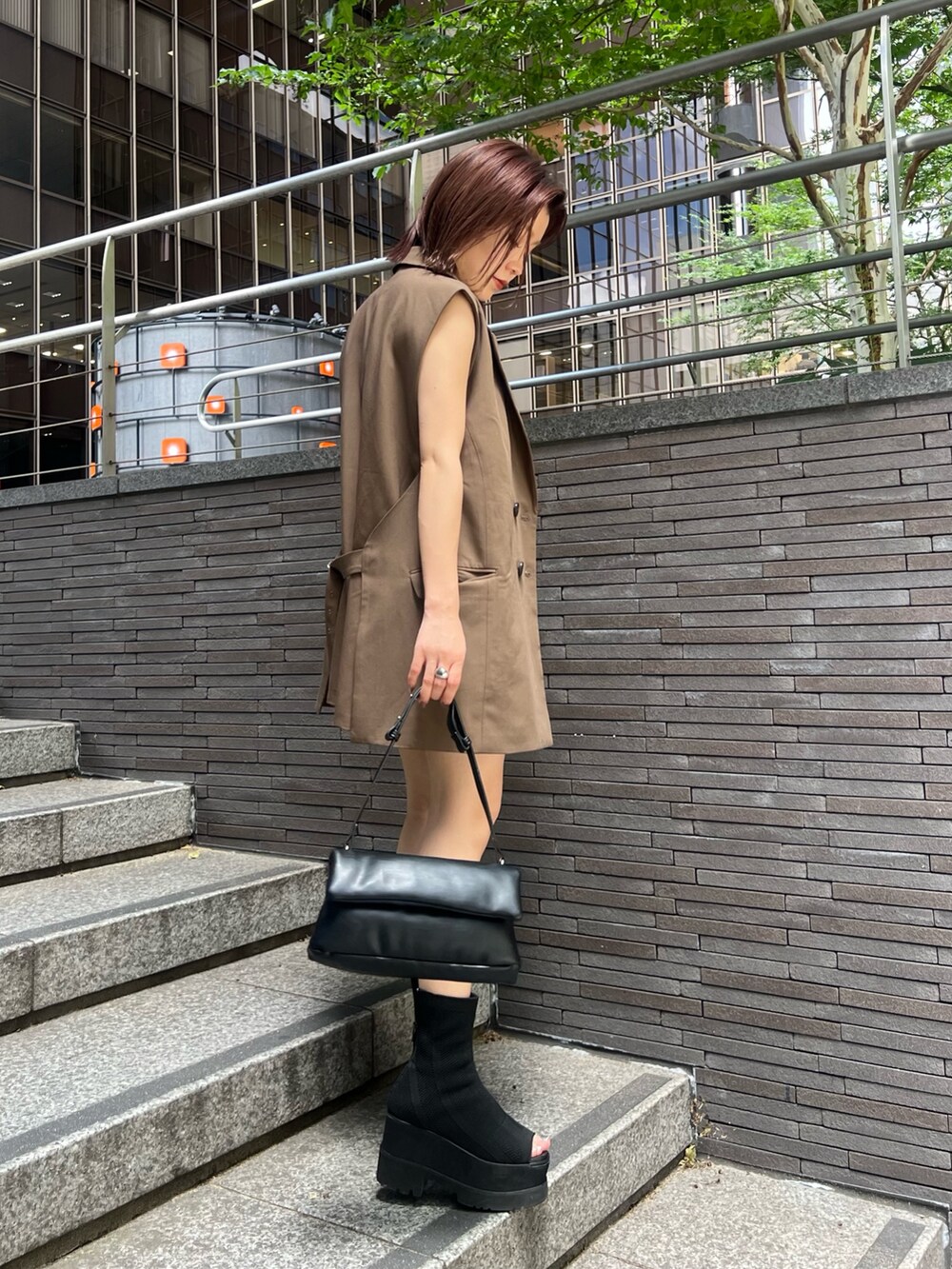 ブラウン系のベスト、ブラウン系のスカート、ホワイト系のニット/セーターを着用したレディースの夏コーディネートの3枚目の写真