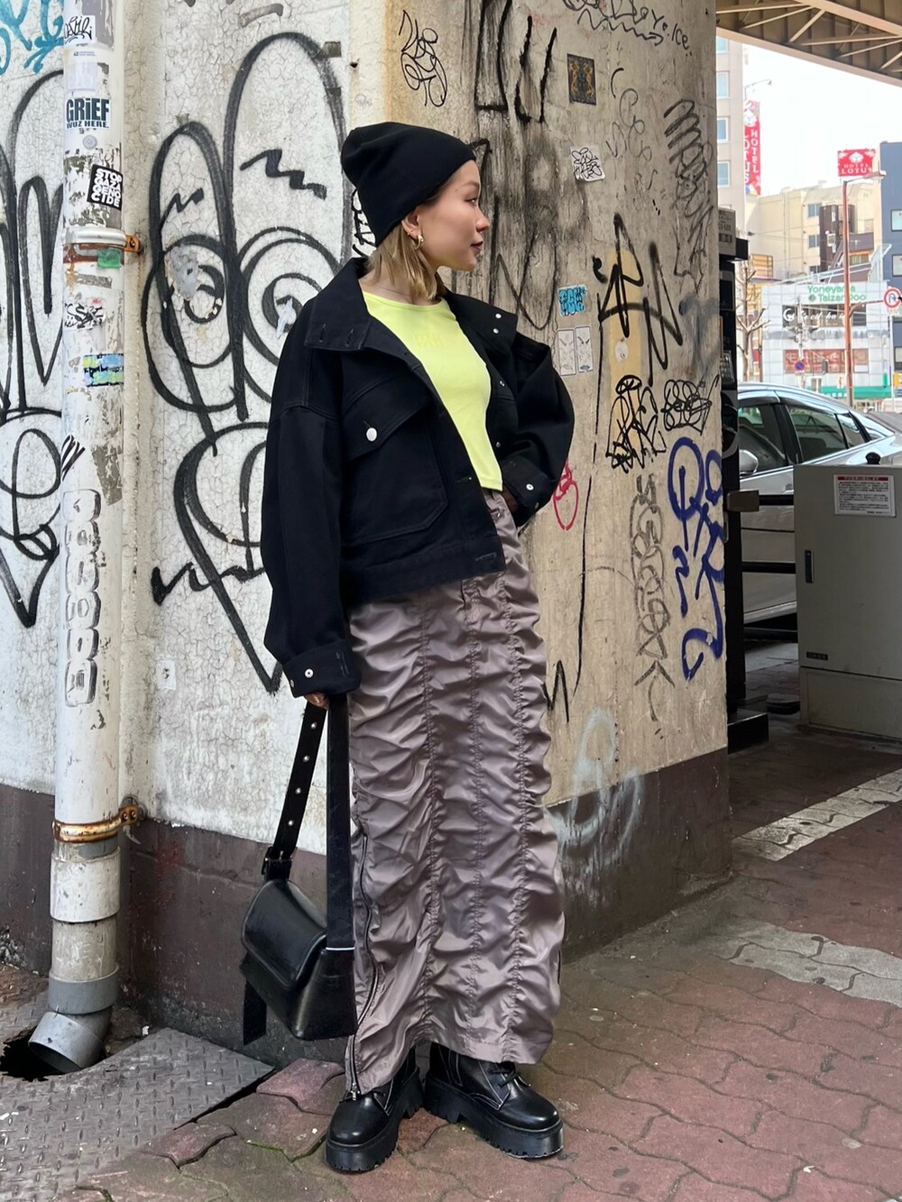 イエロー系のTシャツ/カットソー、ブラック系のデニムジャケット、グレー系のスカートを着用したレディースの春コーディネートの2枚目の写真