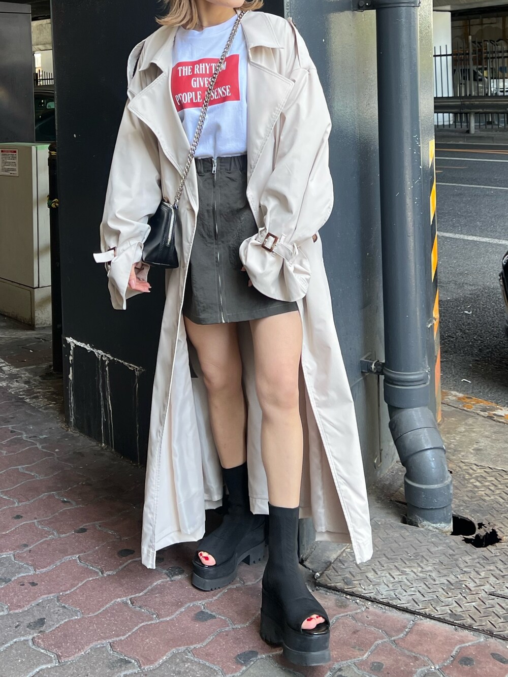 ブラック系のブーツ、ホワイト系のトレンチコート、ホワイト系のTシャツ/カットソーを着用したレディースの春コーディネートの6枚目の写真