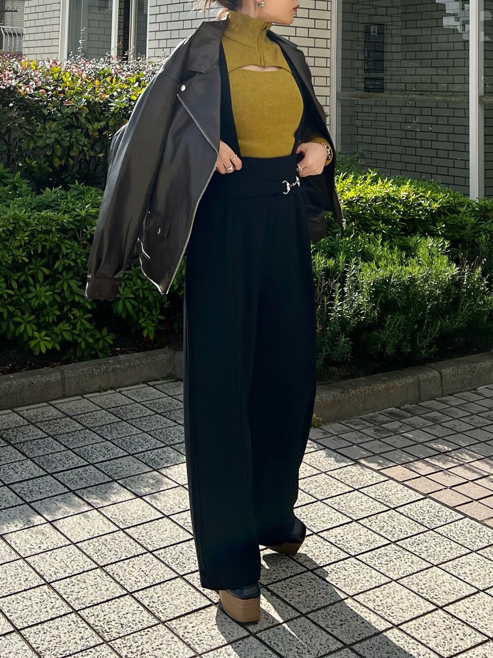 ブラウン系のライダースジャケット、ブラック系のスラックス、ブラック系のローファーを着用したレディースの秋コーディネートの5枚目の写真