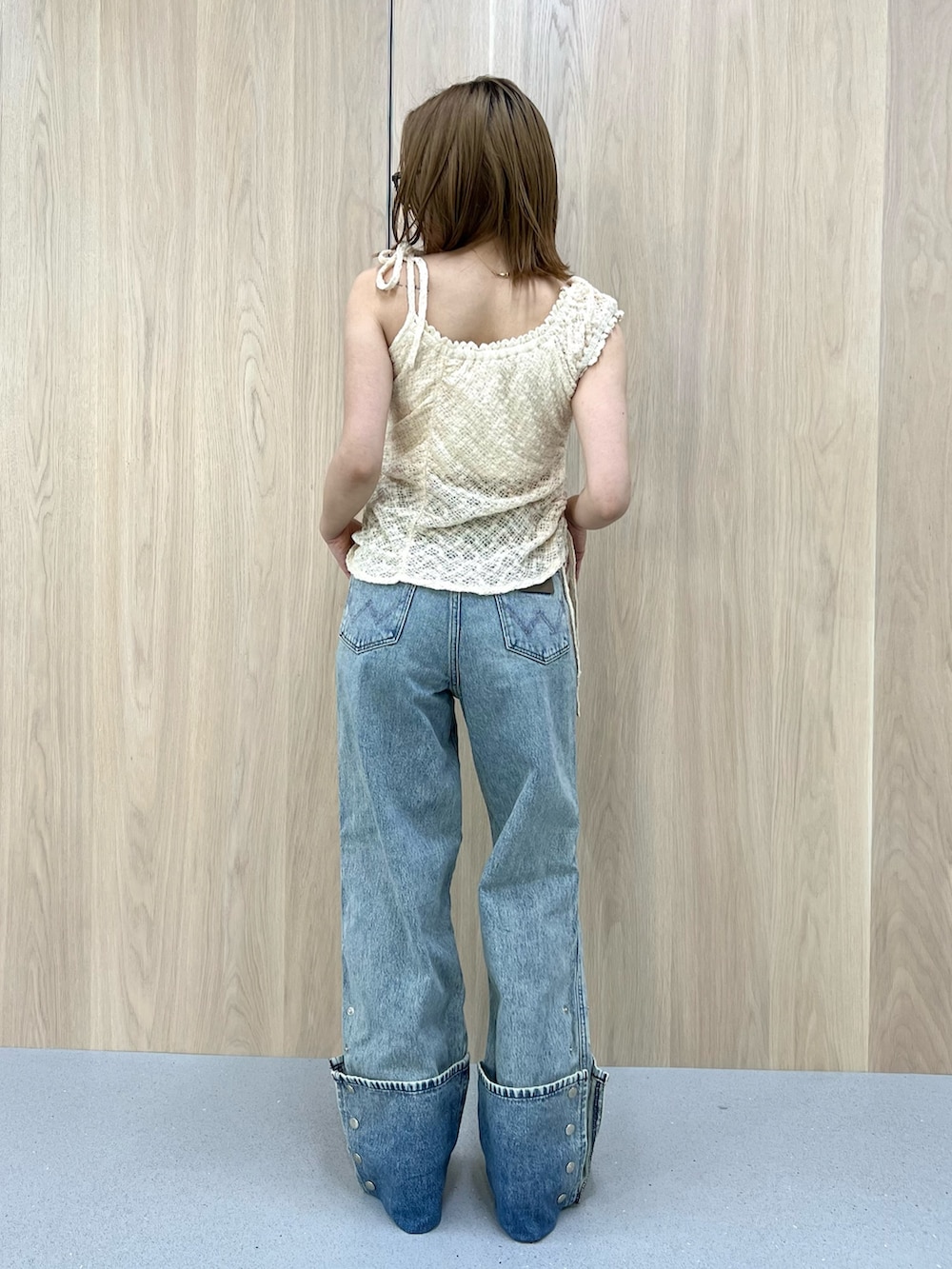 ホワイト系のタンクトップ、ブルー系のデニムパンツ、ブラウン系のブーツを着用したレディースの春コーディネートの3枚目の写真