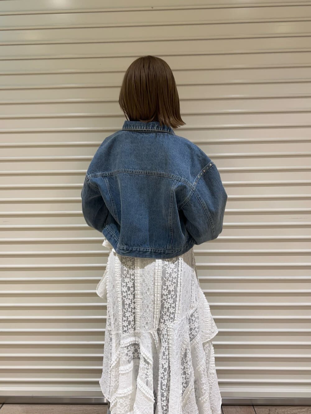 ブルー系のデニムジャケット、ホワイト系のワンピース、グレー系のその他パンツを着用したレディースの春コーディネートの5枚目の写真