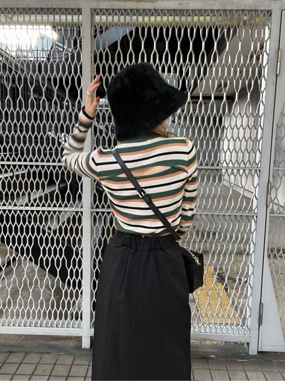 ブラック系のブーツ、ブラック系のショルダーバッグ、ブラック系のスカートを着用したレディースの秋コーディネートの6枚目の写真