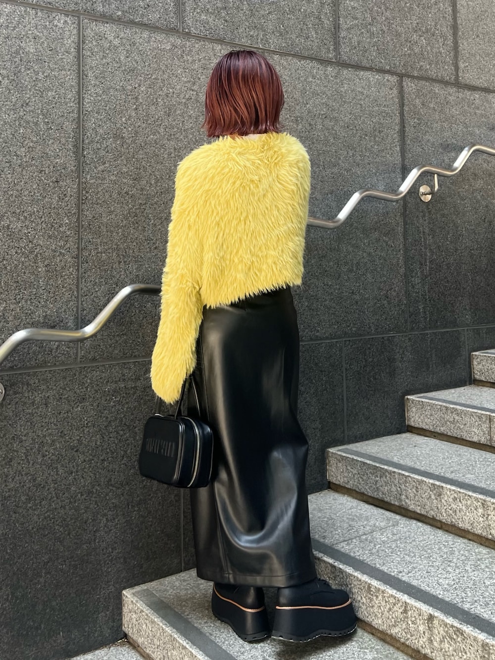 イエロー系のニット/セーター、ブラック系のスカート、ブラック系のブーツを着用したレディースの秋コーディネートの3枚目の写真