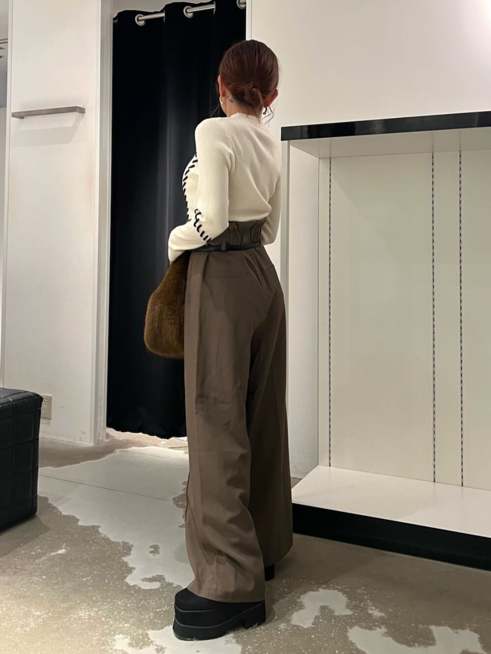 ホワイト系のニット/セーター、ブラック系のブーツ、ブラウン系のハンドバッグを着用したレディースの秋コーディネートの2枚目の写真